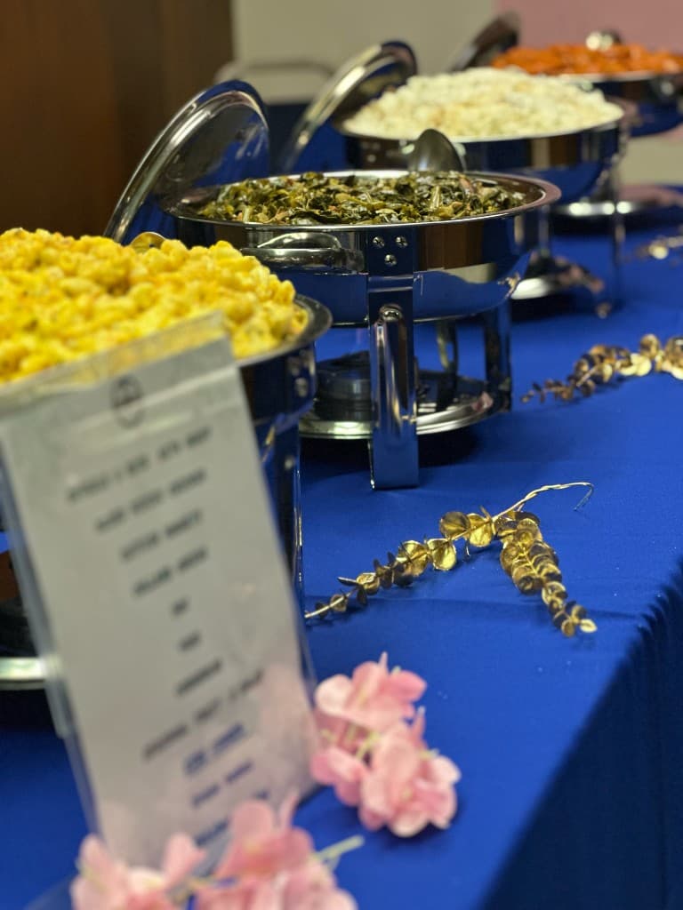Full buffet line with mac and cheese, greens, and rice served at a Riverside event