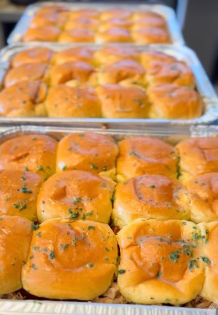 Trays of golden glazed dinner rolls topped with herbs