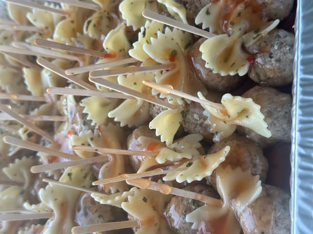Meatball and bowtie pasta appetizer skewers on a platter